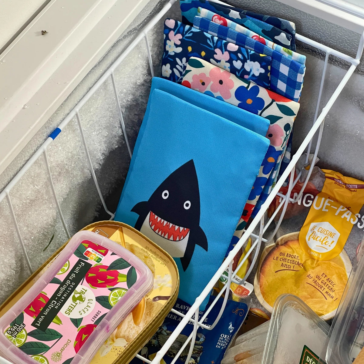 Assorted ice packs with colorful designs in a refrigerator.